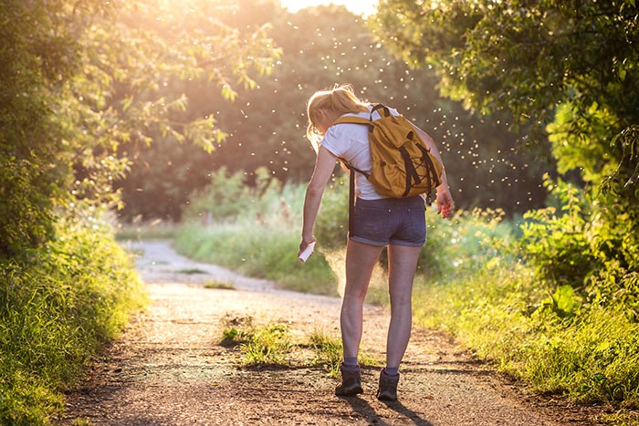Femme utilisant un insecticide pour éloigner les insectes